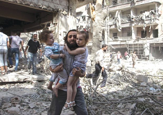 体制軍による樽爆弾被害にあった建物跡で二人の娘を抱える父親（AFP）