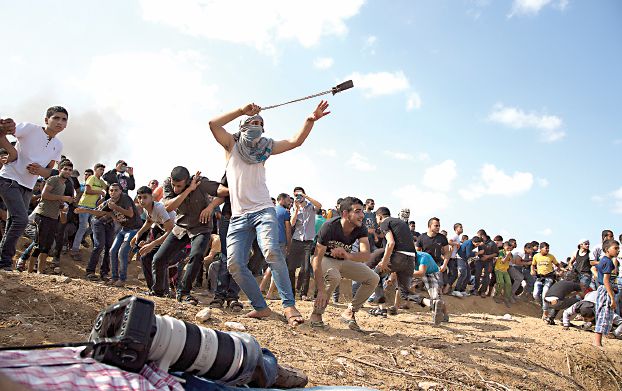 イスラエル兵に投石するガザのデモ参加者ら。昨日。（AP）