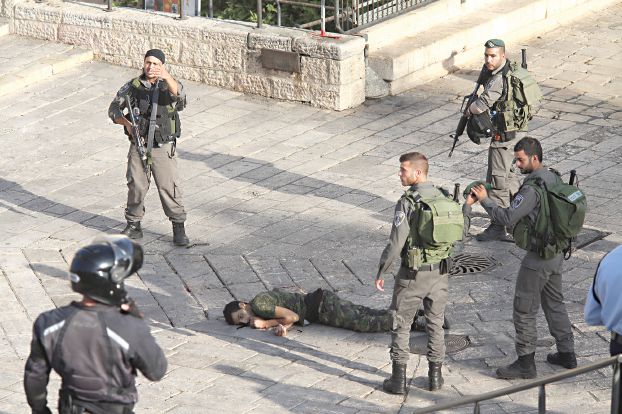 昨日の占領下エルサセム、ナイフ攻撃を試みたとしてイスラエル兵に銃撃されたパレスチナ青年の遺体を囲む兵士たち（AP）