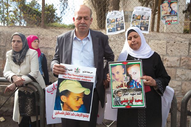 昨日（11月30日）占領下エルサレムのイスラエル中央裁判所の外で息子の写真を掲げるアブー・フダイル少年の両親（AFP）