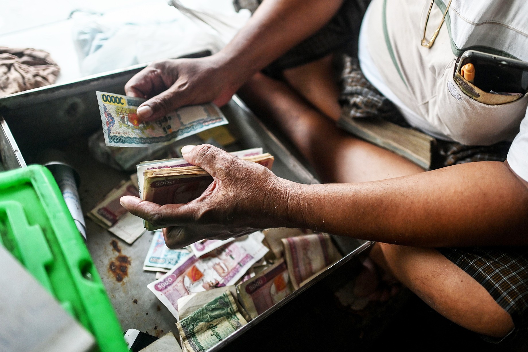 ヤンゴン中心部パンソーダン通りのある店舗で紙幣を数える店主（イェアウントゥ/ Getty Images）